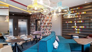 Un hall d’entrée moderne avec un canapé bleu, une table en bois et un mur orné de motifs.