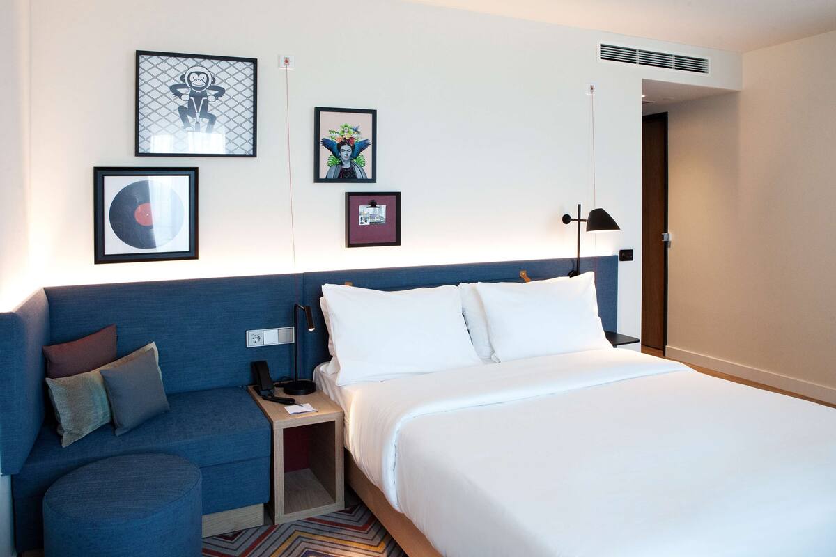 Ein Hotelzimmer mit Bett, einer Couch, einem Nachttisch und Wandbildern.