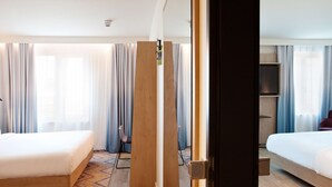 Une chambre d’hôtel avec deux lits, une cloison en bois et une vue sur la ville.