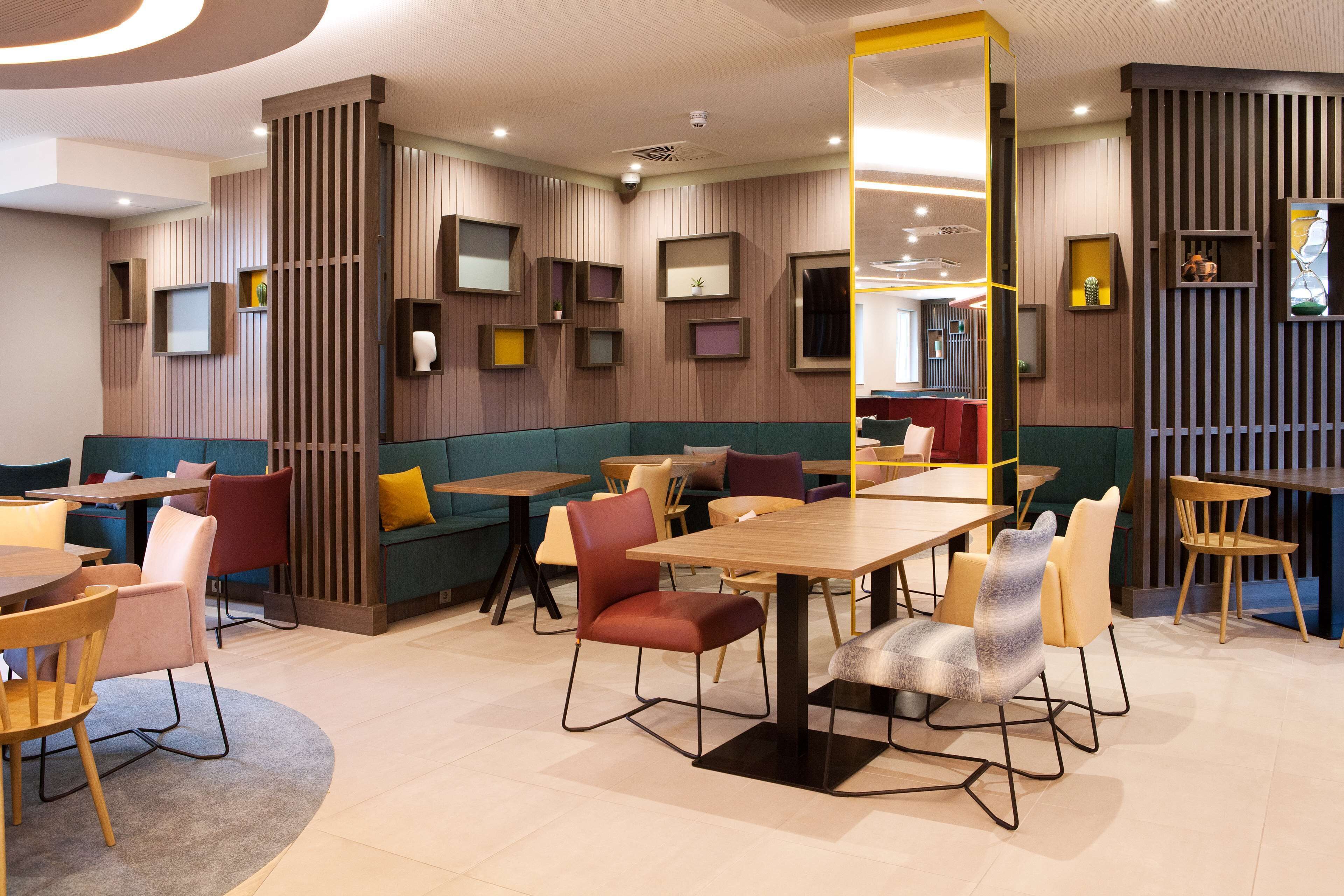 Un restaurante moderno con cabinas y mesas, paneles de madera y diferentes opciones de asientos.