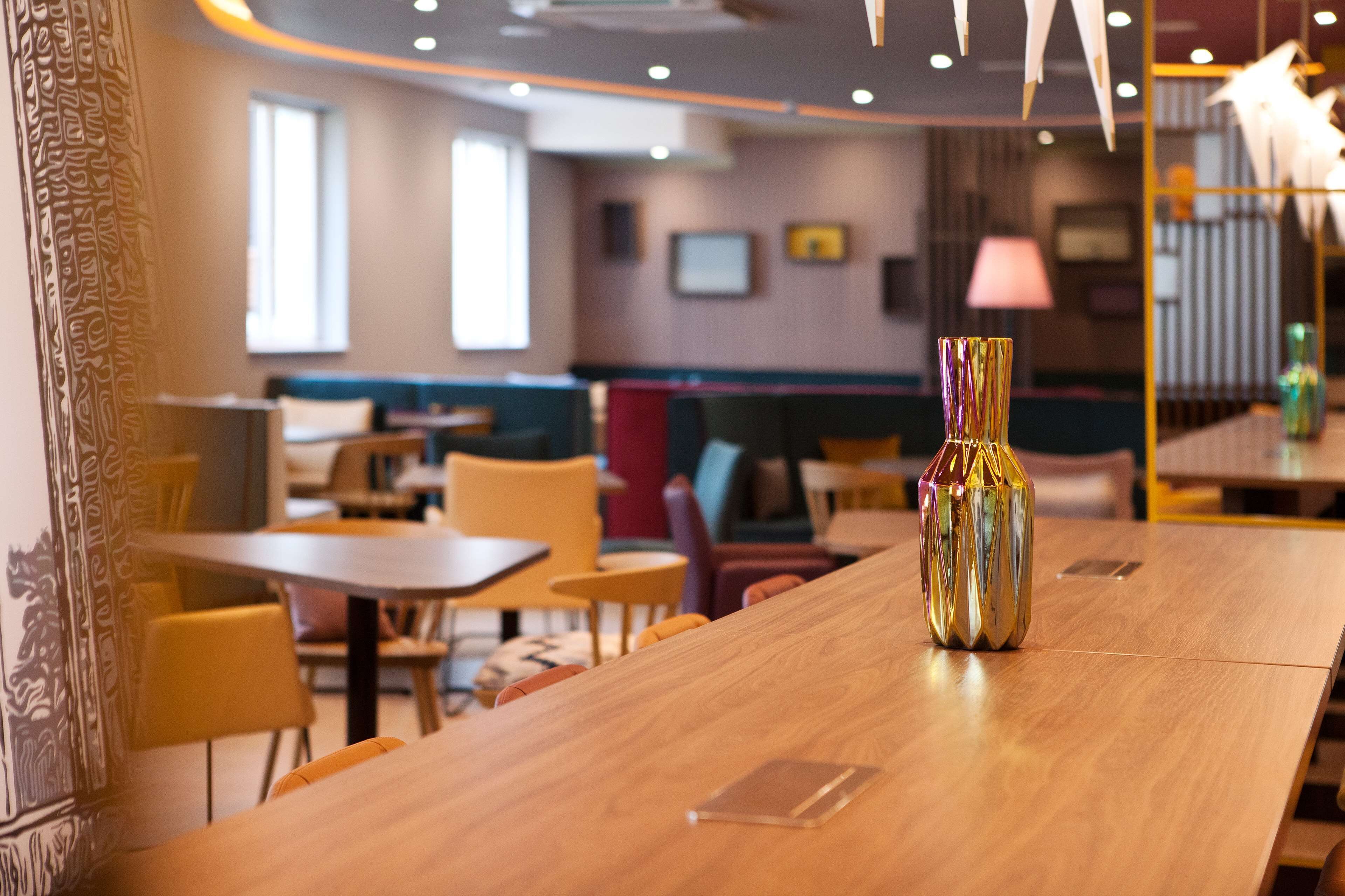 Ein Restaurant mit Holztischen und -stühlen, eine dekorative Vase auf einem Tisch und Blick auf den Speisesaal.