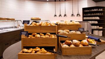 Eine Bäckereiaufstellung mit verschiedenen Gebäcken und Brot in Holzschachteln, beschriftet mit Namen wie „Croissants“ und „Kruste.“