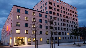 Un hôtel à plusieurs étages au design moderne, doté d’une entrée imposante et d’une enseigne lumineuse.
