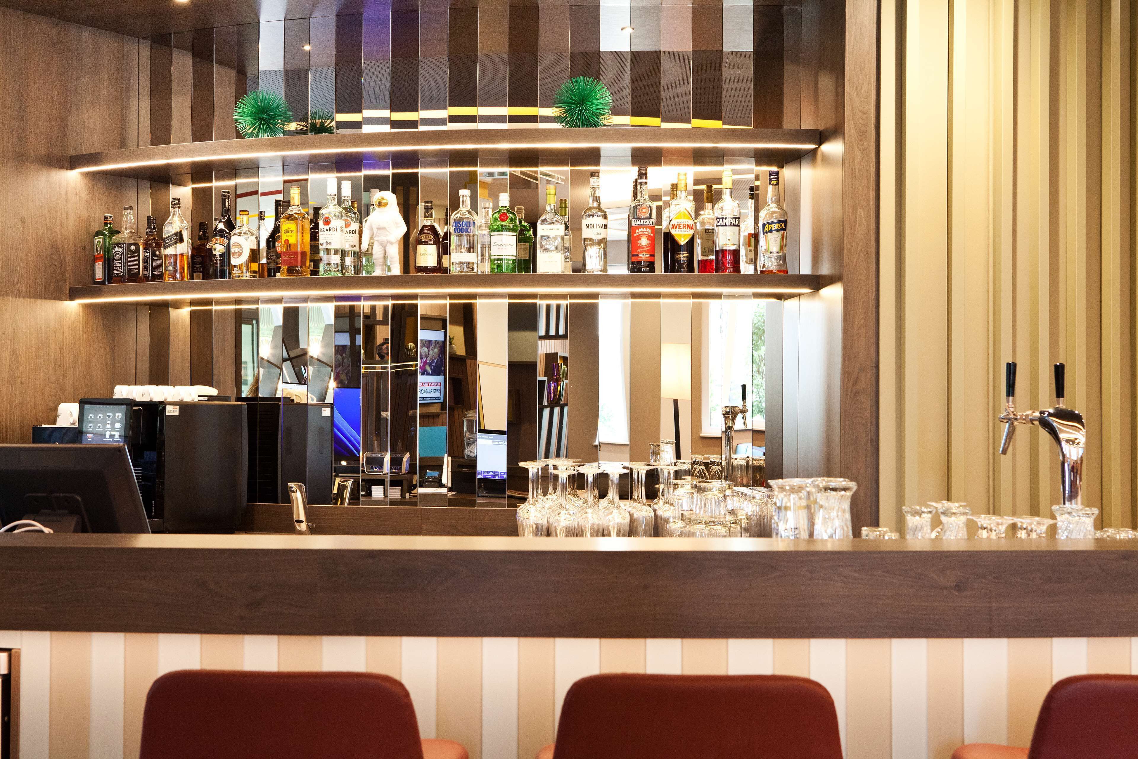 A bar area with multiple shelves of liquor bottles, a cash register, and a bar tap.