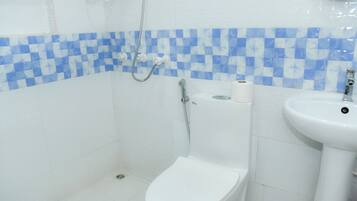 Un bany amb vàter blanc, un lavabo i una dutxa.
