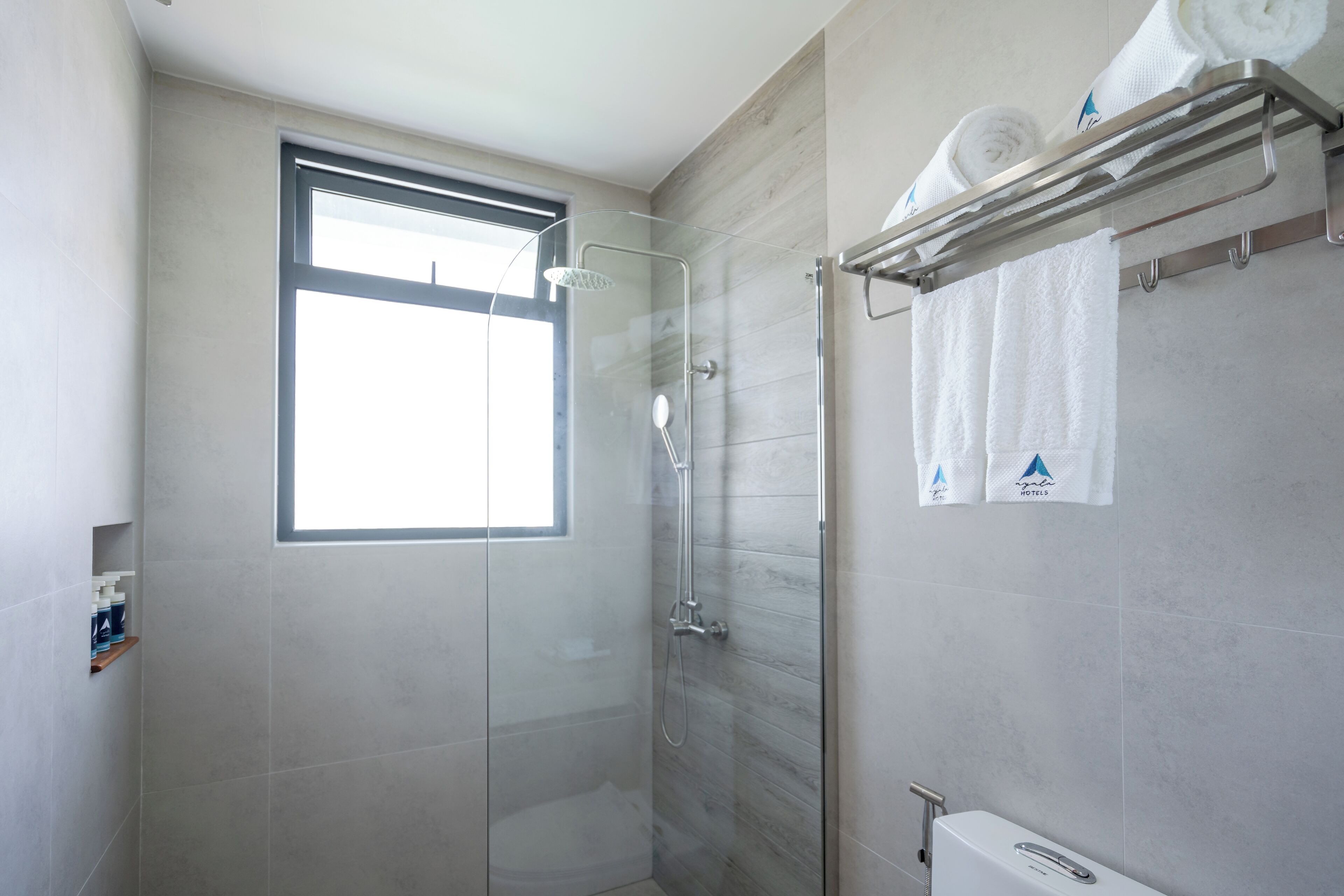 Een moderne badkamer met een douchecabine, een toilet en een handdoekrek met handdoeken.