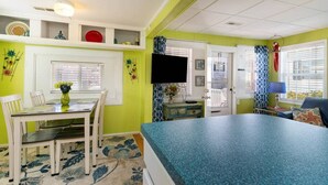 Una habitación con una mesa de comedor, sillas, televisor y cama.