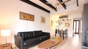 Ein modernes Wohnzimmer mit einer schwarzen Ledersofa, einem Holztisch und einem Essbereich mit Tisch und Stühlen. Es gibt einen Deckenventilator, einen Kamin und Kunstwerke an den Wänden.