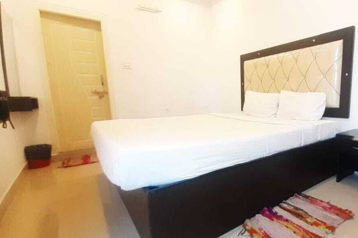 Una cama individual con cabecera, una mesita de noche y una pequeña alfombra en el suelo.