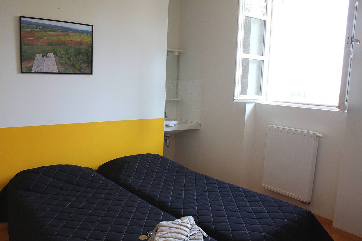 A room with two beds, a window, and a radiator.