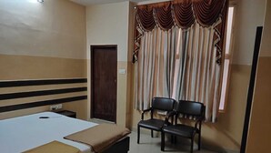 Ein Hotelzimmer mit einem Bett, zwei Sesseln, einem kleinen Tisch und einer Tür.