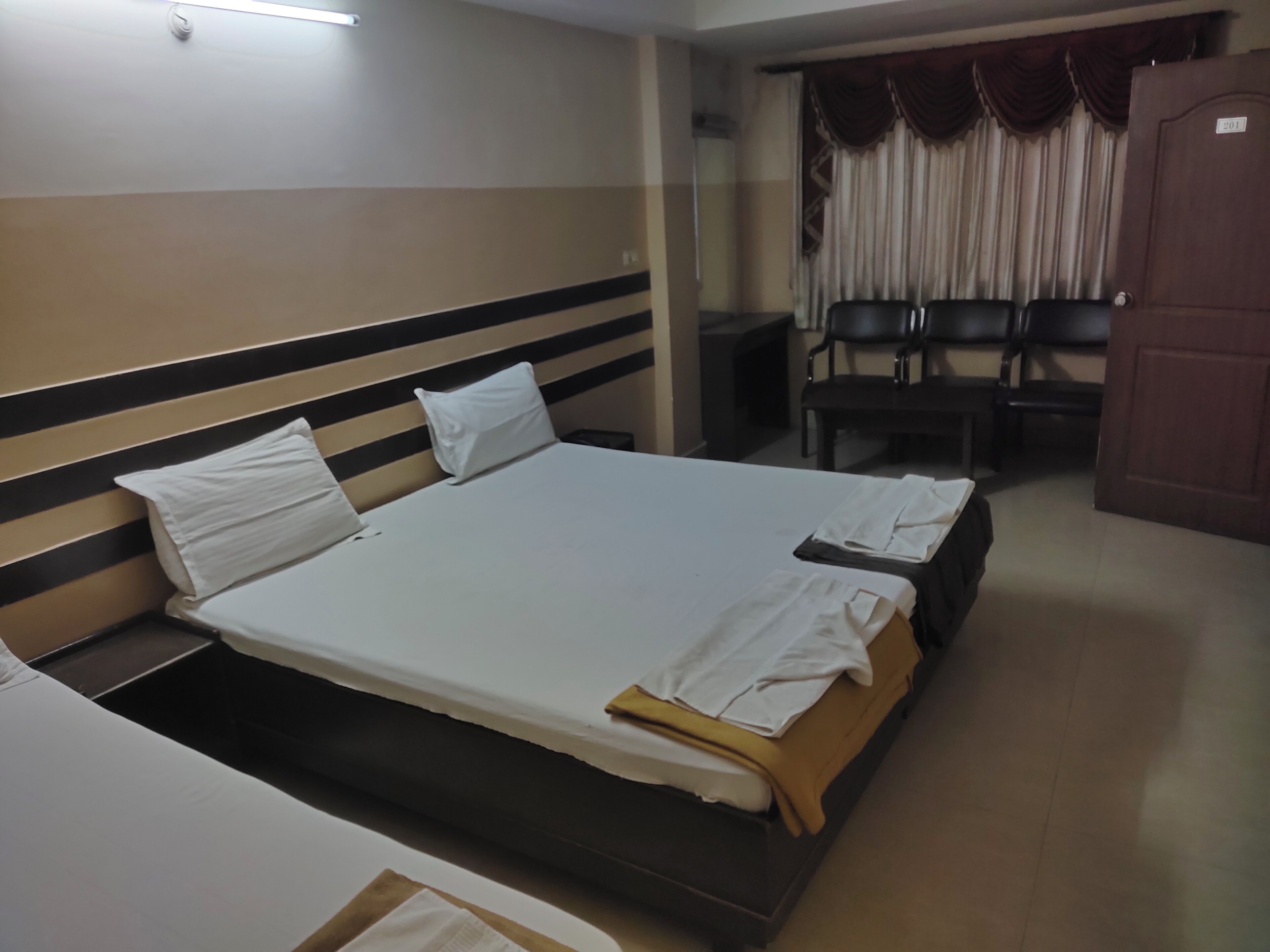 A hotel room with a large bed, two bedside tables, a desk, and a chair.