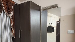 Ein Zimmer mit Kleiderschrank, Schreibtisch, Stuhl und Mülleimer.