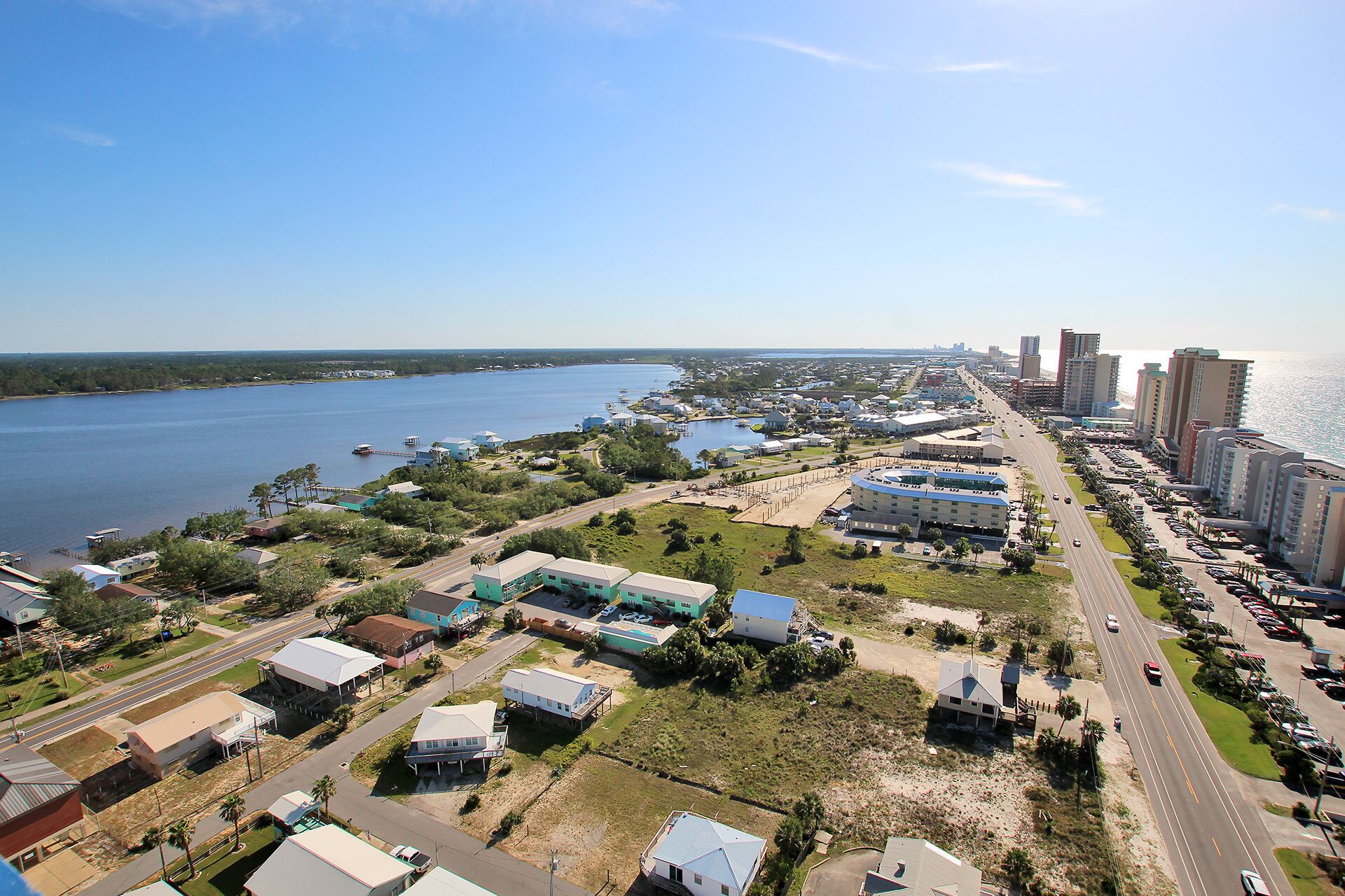 An aerial view of a coastal town with a marina, residential buildings, and a highway.