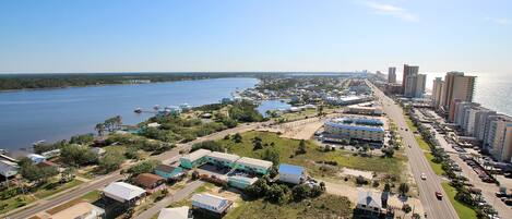 An aerial view of a coastal town with a marina, residential buildings, and a highway.