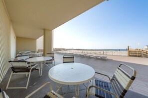Un espace extérieur abrité, doté de tables et de chaises, offrant une vue sur la plage et comprenant une terrasse en bois.