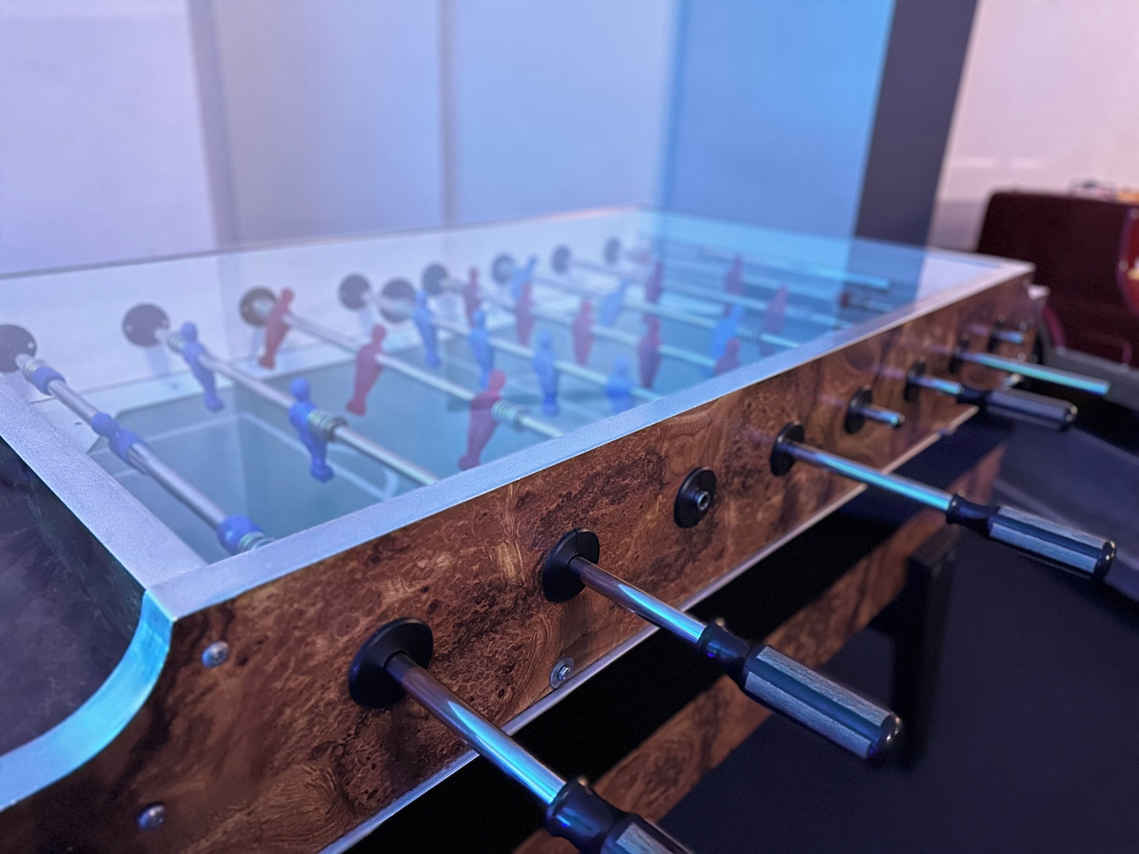 A foosball table with a wooden base and glass top.