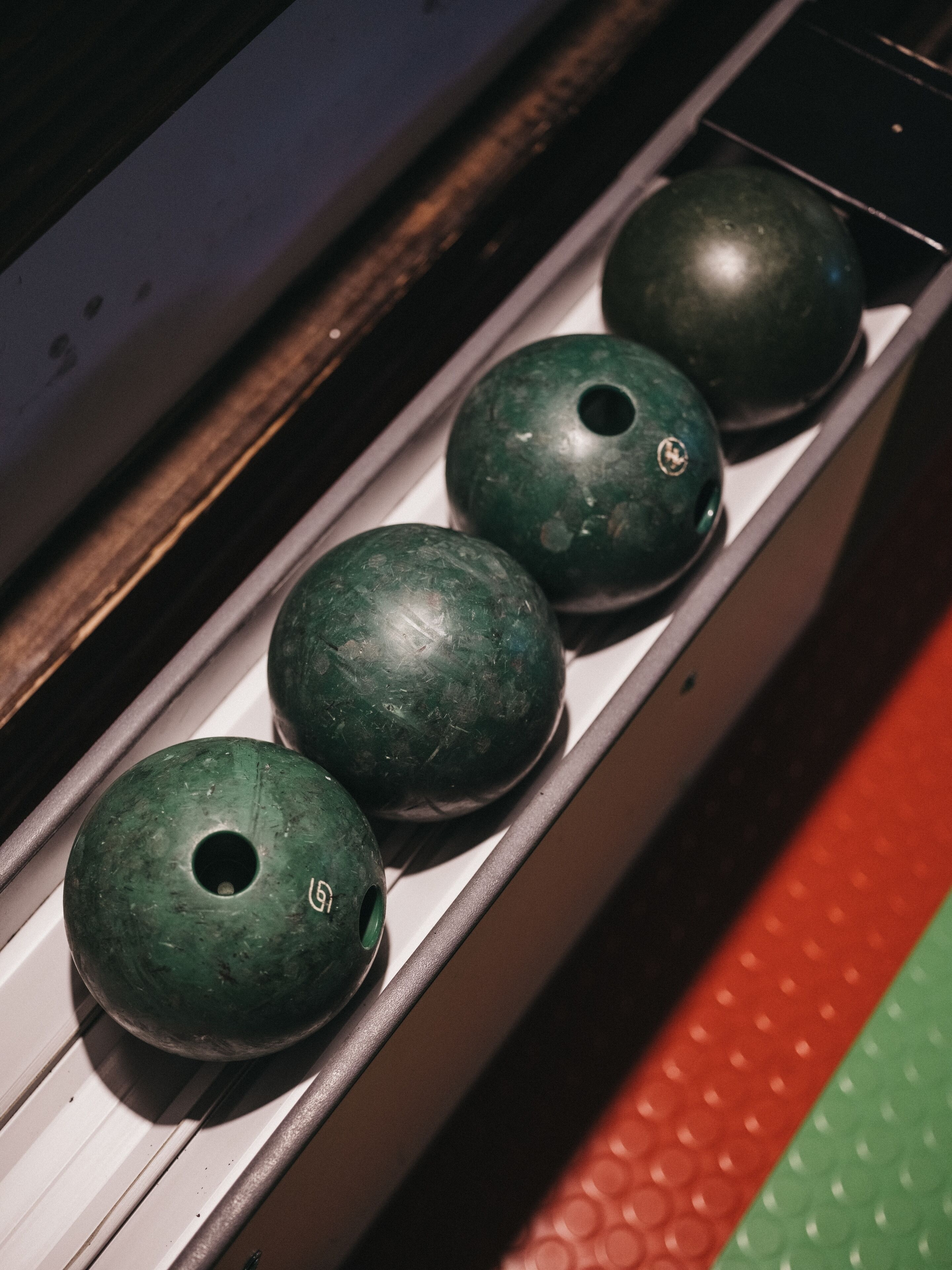 Una hilera de bolas de bolos verdes en un soporte.
