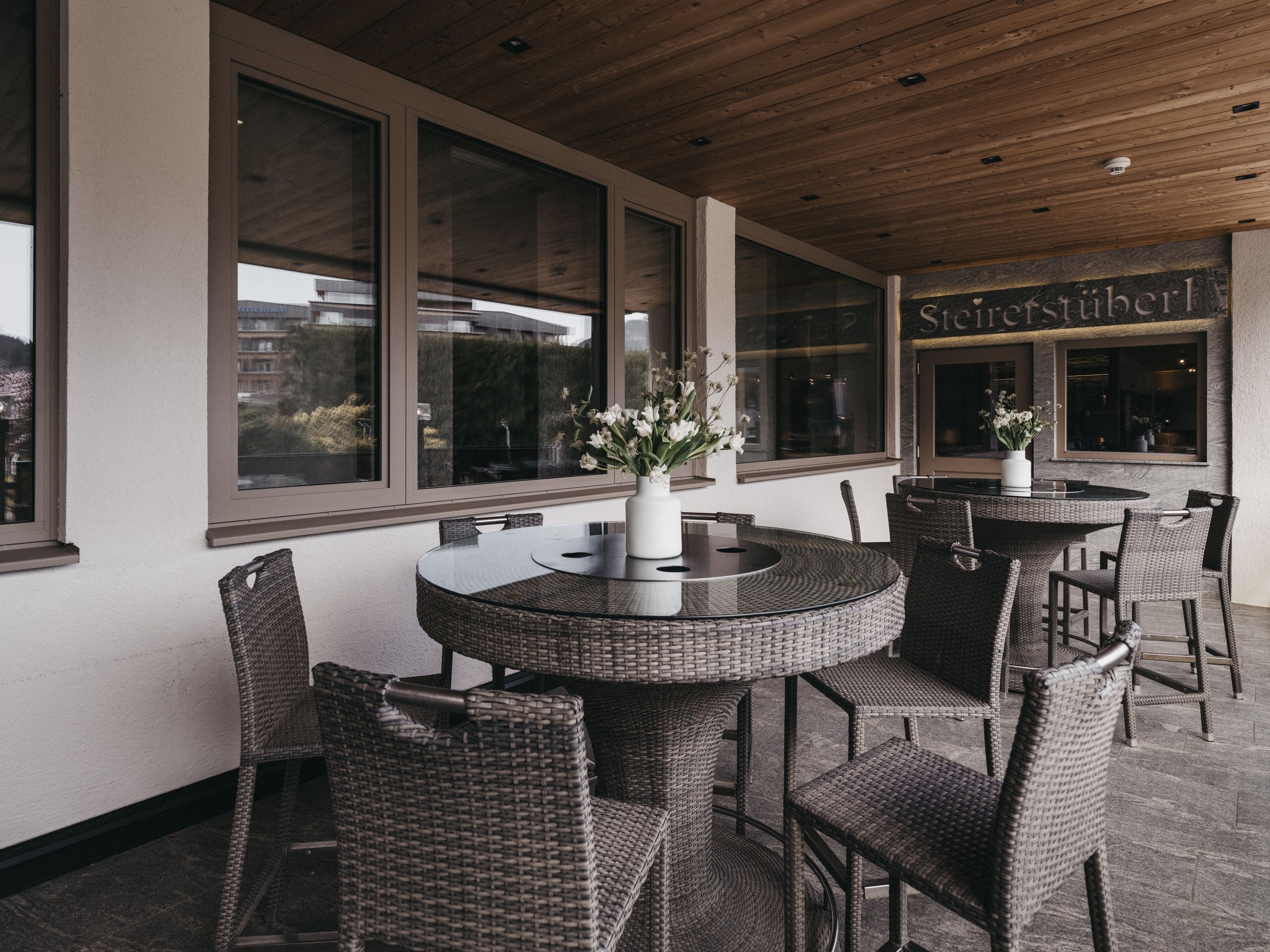 An outdoor seating area with wicker furniture and large windows.
