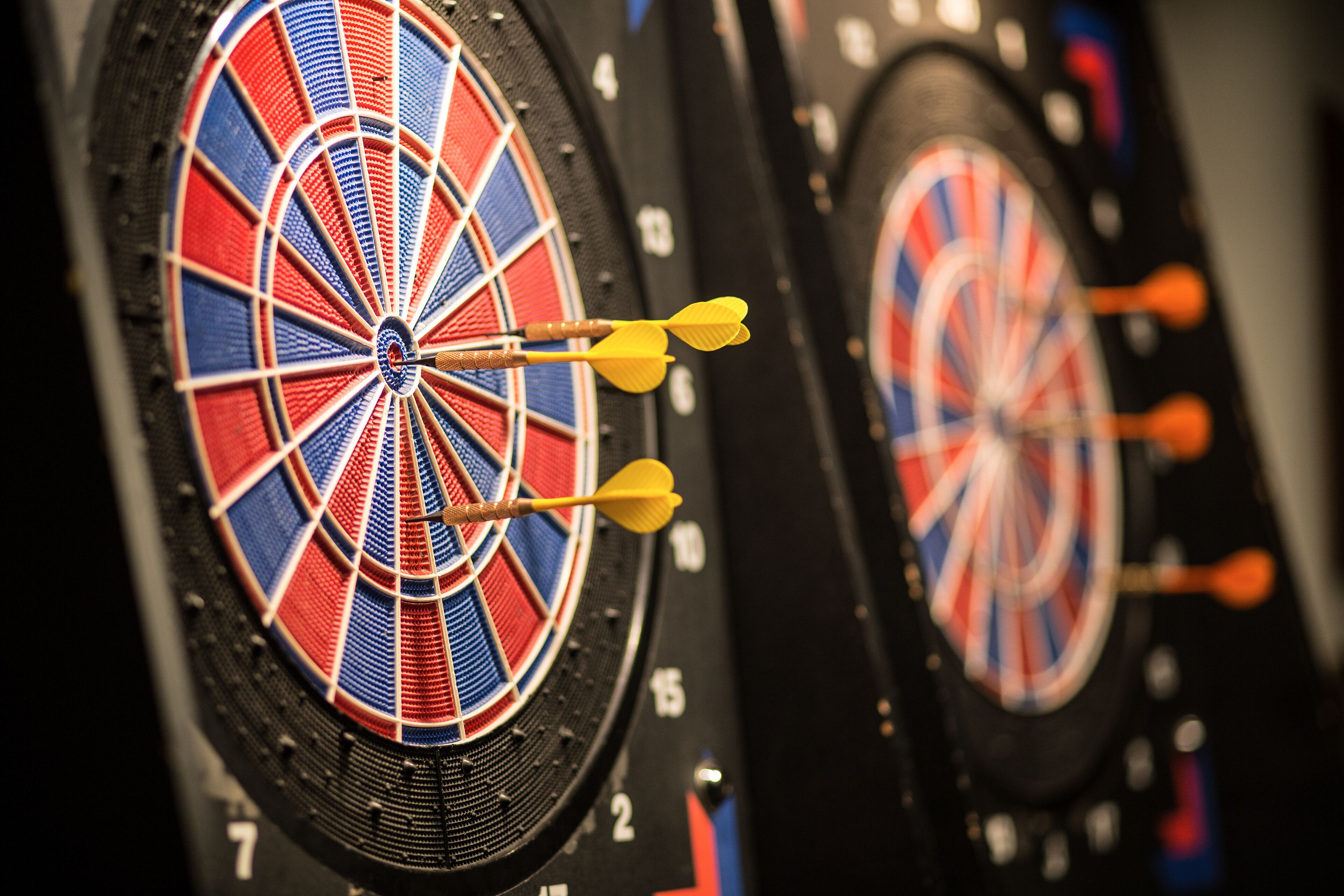Two dartboards with darts in the center, both featuring a red, white, and blue color scheme.