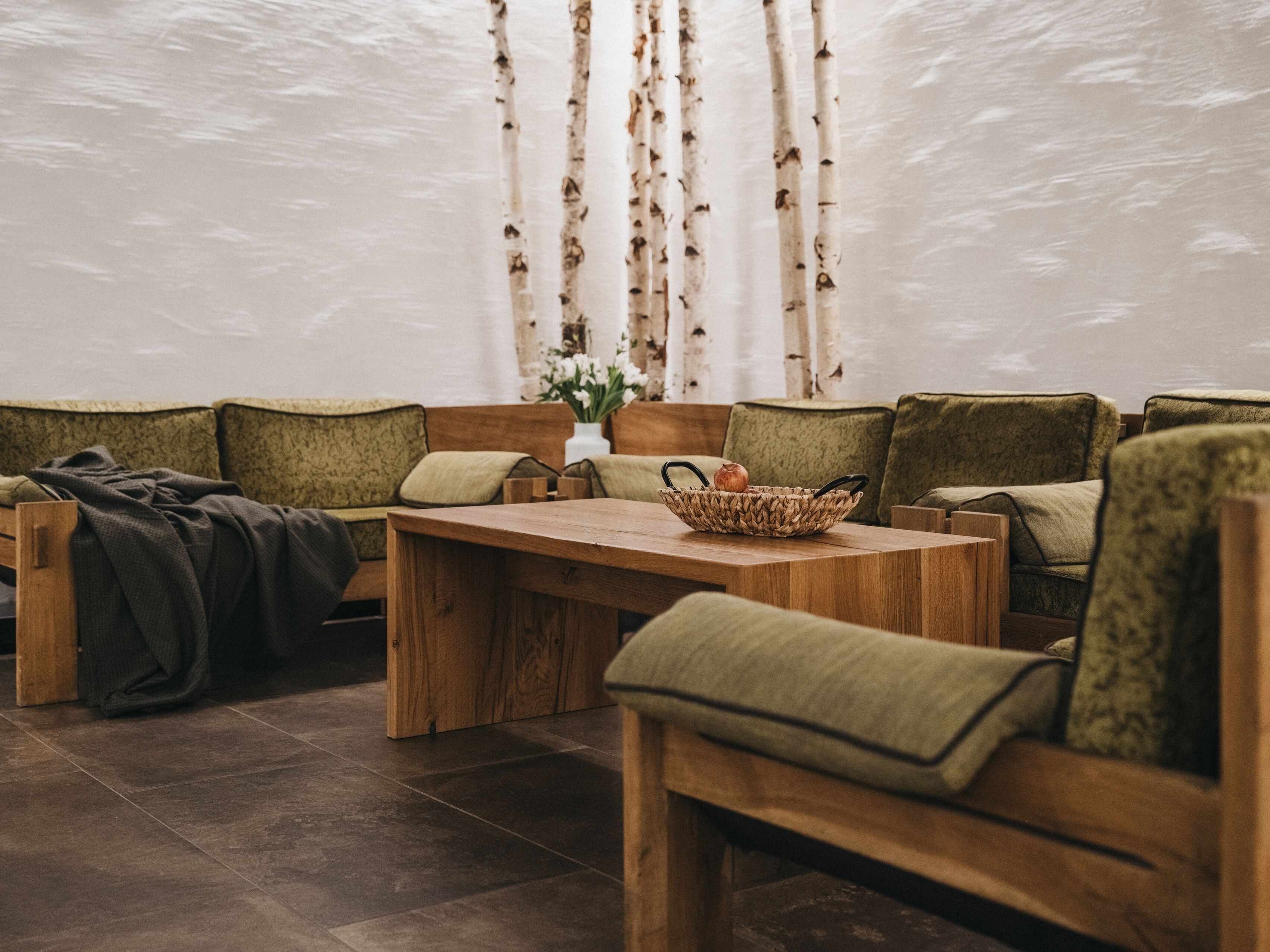 Un rincón acogedor con una mesa de madera, sillas tapizadas en verde y una cesta tejida sobre la mesa.