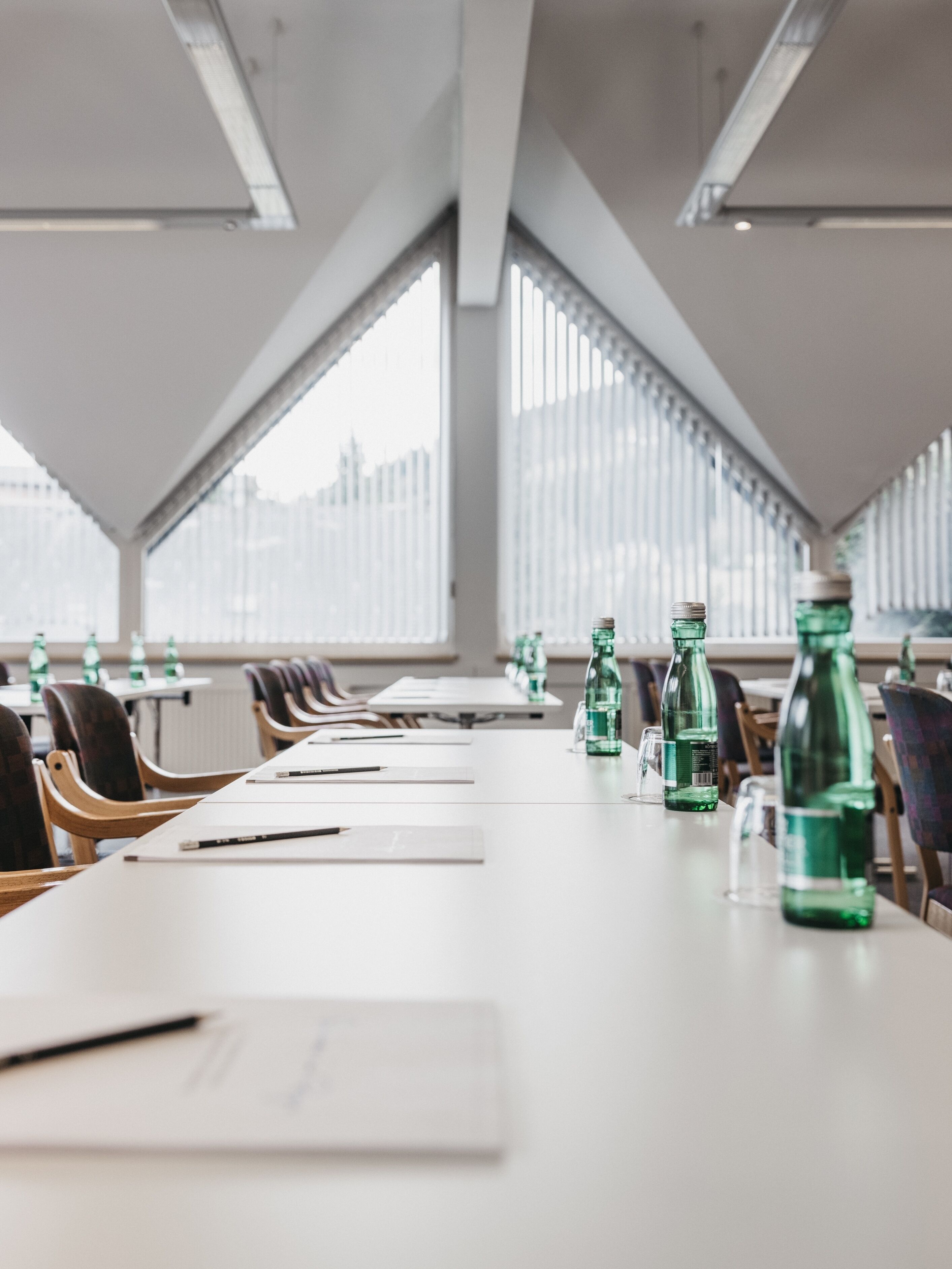 Une salle de conférence avec une longue table, des chaises et des bouteilles d’eau.