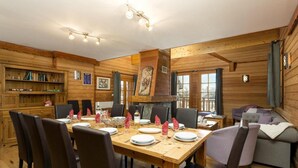 Un intérieur en bois avec une table à manger dressée pour quatre personnes, entourée de chaises.