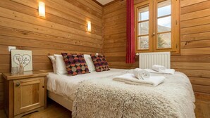 Une pièce chaleureuse avec des murs en bois, un lit, un tapis moelleux et une table de chevet avec une lampe.