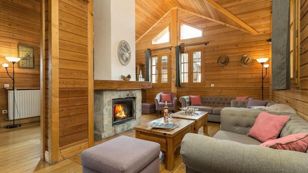 L’intérieur d’un chalet confortable, avec une cheminée en pierre, des murs en bois et un coin salon accueillant.