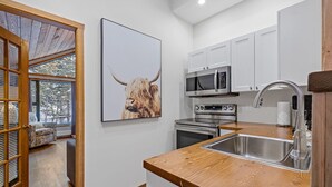 Eine moderne Küche mit weißen Schränken, Edelstahlgeräten und einer Holz Arbeitsplatte.