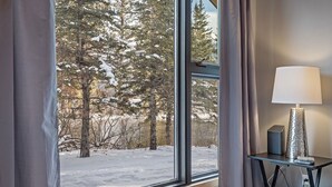 Ein Zimmer mit großem Fenster und Blick auf schneebedeckte Bäume und einen klaren Himmel.
