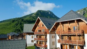 A row of wooden chalets with balconies, set against a backdrop of a mountain and clear sky. - Wifi, 200m from ski slopes, swimming pool, parking, 50-70m², Saint Sorlin d'Arves (Saint-Sorlin-d'Arves)