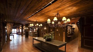 A spacious lobby with a wooden ceiling, a central table with a plant, and multiple chandeliers. - 100m from ski slopes, fitness, swimming pool, sauna, balcony, fireplace or stove, tv, ski locker (Les Arcs)