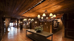 A spacious lobby with a wooden ceiling, a central table with a plant, and multiple chandeliers. - 100m from ski slopes, fitness, swimming pool, sauna, balcony, fireplace or stove, tv, ski locker (Les Arcs)