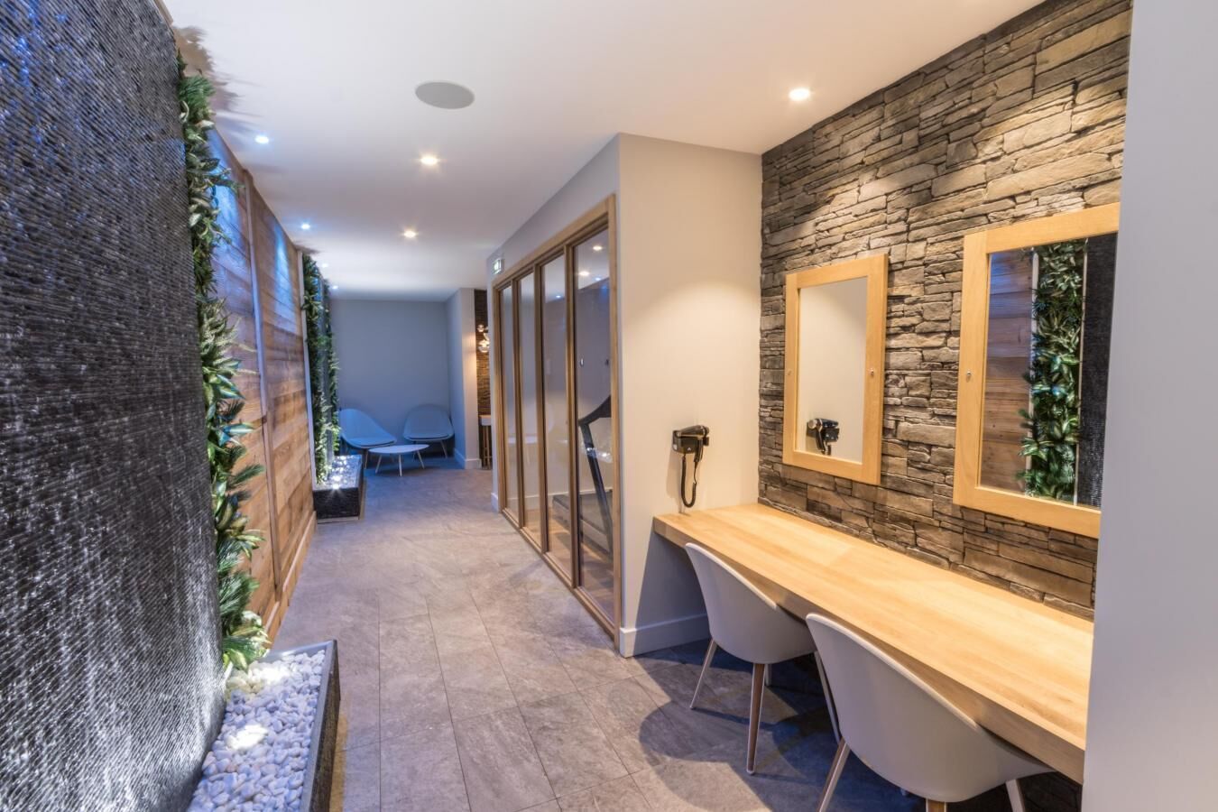 Un baño moderno con pared de piedra, tocador de madera y zona de ducha.