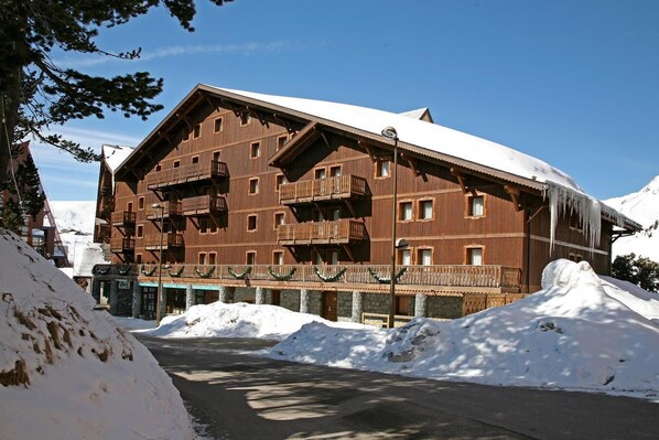Un edificio grande de madera con varios balcones y un techo cubierto de nieve.
