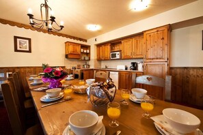 Un comedor acogedor con muebles de madera, una araña y una cocina al fondo.
