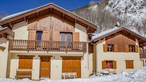 A chalet-style building with wooden balconies, large wooden doors, and a snow-covered landscape. - Chalet, sauna, terrace, fireplace or stove, parking, tv, ski locker, 110m² (Saint-Martin-de-Belleville)