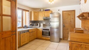 A kitchen with wooden cabinets, a stainless steel refrigerator, a microwave, a toaster, and a coffee maker. - Chalet, sauna, terrace, fireplace or stove, parking, tv, ski locker, 110m² (Saint-Martin-de-Belleville)