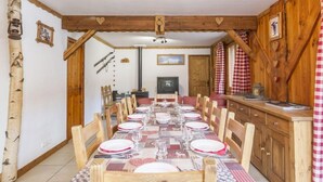 A dining area with a long wooden table set for a meal, flanked by wooden chairs. - Chalet, sauna, terrace, fireplace or stove, parking, tv, ski locker, 110m² (Saint-Martin-de-Belleville)