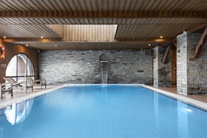 Ein Innenpool mit Steinwänden und Holzbalken.