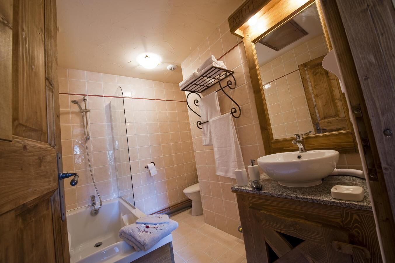 A bathroom with a bathtub, a shower, a sink, and a wooden vanity.