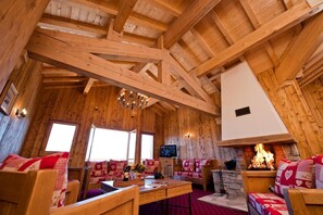 A cozy wooden cabin interior with a fireplace, wooden furniture, and a television.