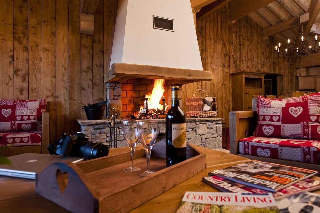 A cozy room with a fireplace, wooden furniture, and a bottle of wine on a table.