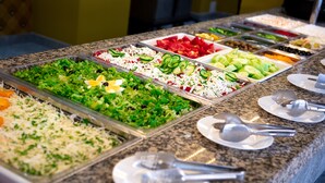 En buffet med et bredt udvalg af mad, herunder salater, frugt og grøntsager.