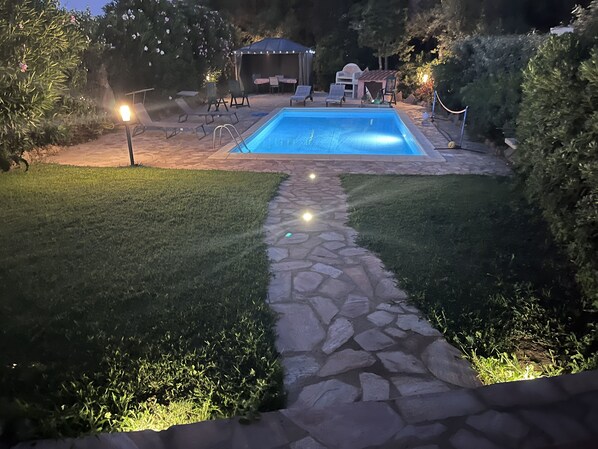 A backyard with a swimming pool, stone pathway, and outdoor furniture. - Charming Villa with Private Pool - Near the Beaches and Stintino (Punta de Su Turrione)