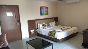 Una habitación de hotel con una cama, una mesita de noche, una silla y un cuadro en la pared.