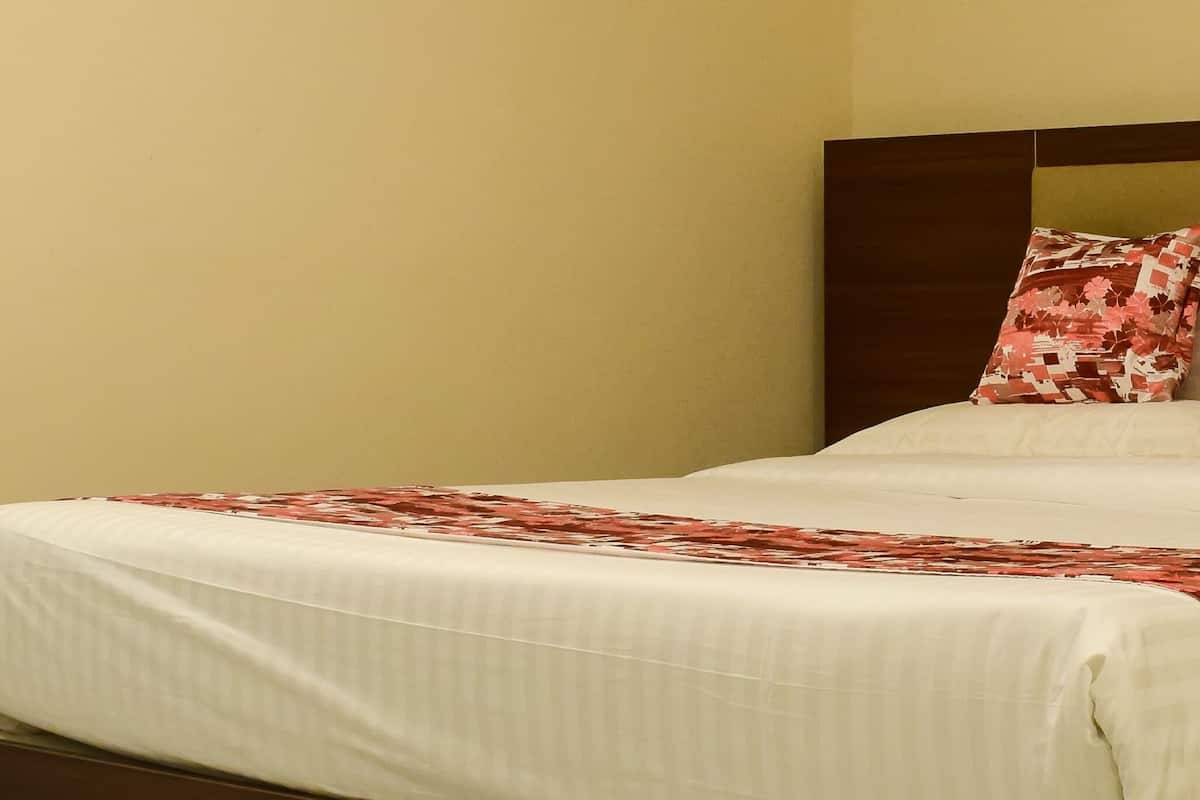A bedroom with a bed, a wooden headboard, and an air conditioning unit on the wall.