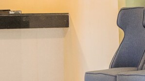 Un área de recepción moderna con un mostrador, una silla tapizada en azul y una partición de vidrio.