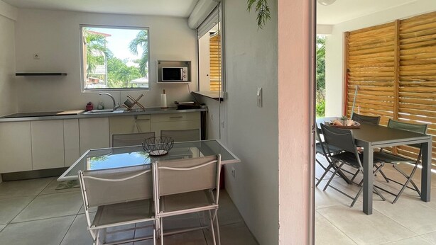 Cozinha moderna com uma mesa de jantar de vidro, micro-ondas e planta pendente.